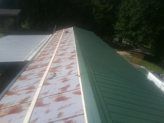 Old rusted panels beside newly installed green metal roofing — Wind Damage Roof Repair by Roofing Brothers in Zellwood