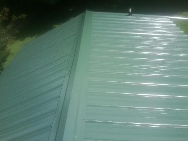 New green metal panels meeting at the ridge of a roof — Flat Roof Repair work by our crew in Zellwood