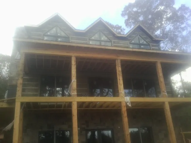 Dormers and porch framing on a large log home under construction — Roof Coating work by our crew in Zellwood