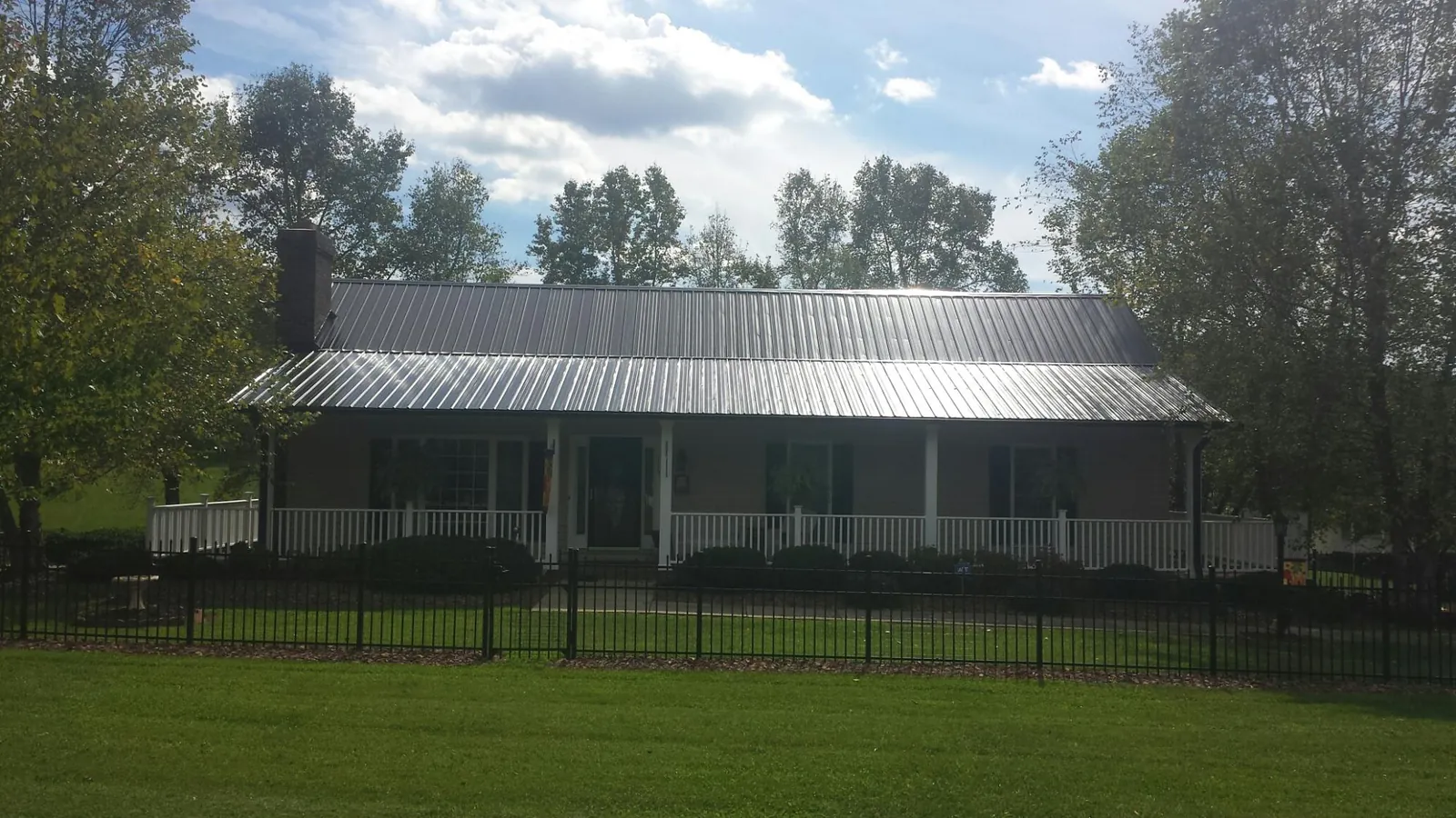 Gray metal roof on a brick ranch with a full width front porch — Gutter Guard Installation work by our crew in Zellwood