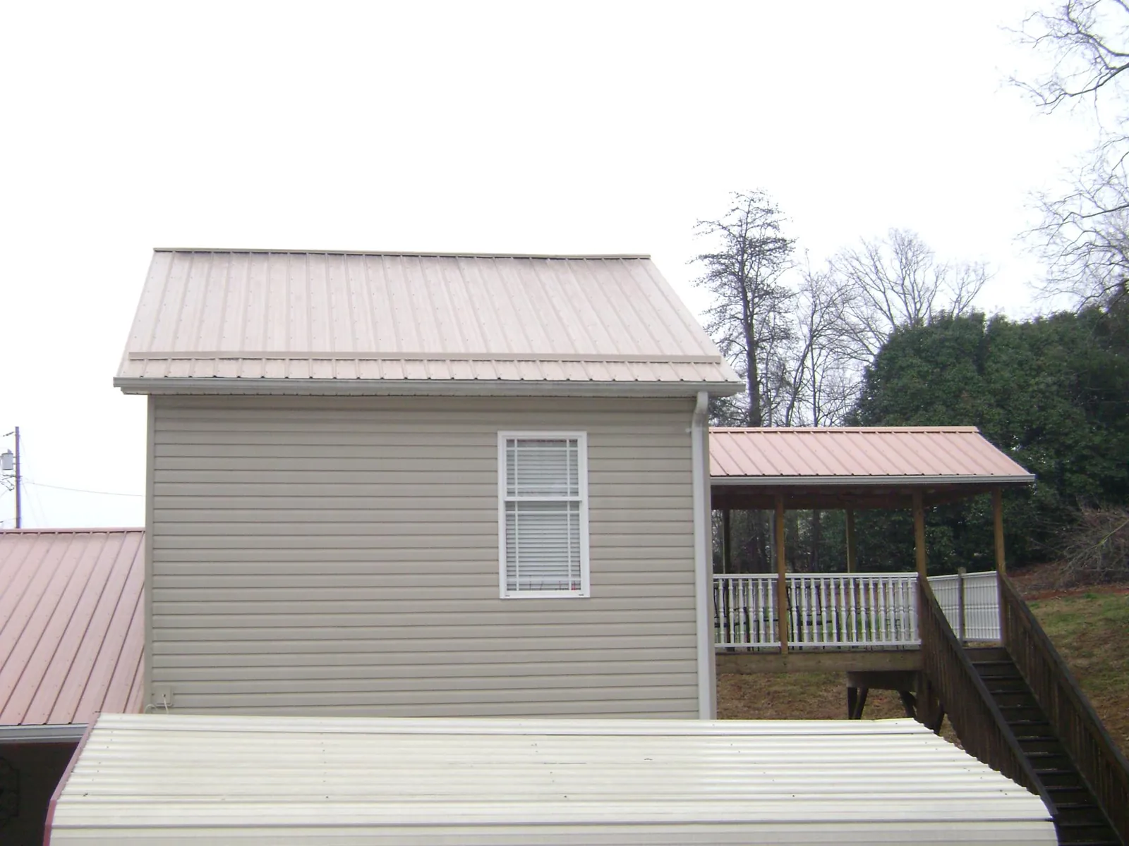 Tan metal roofs on a two story addition and attached porch, from a Roof Replacement job in Zellwood