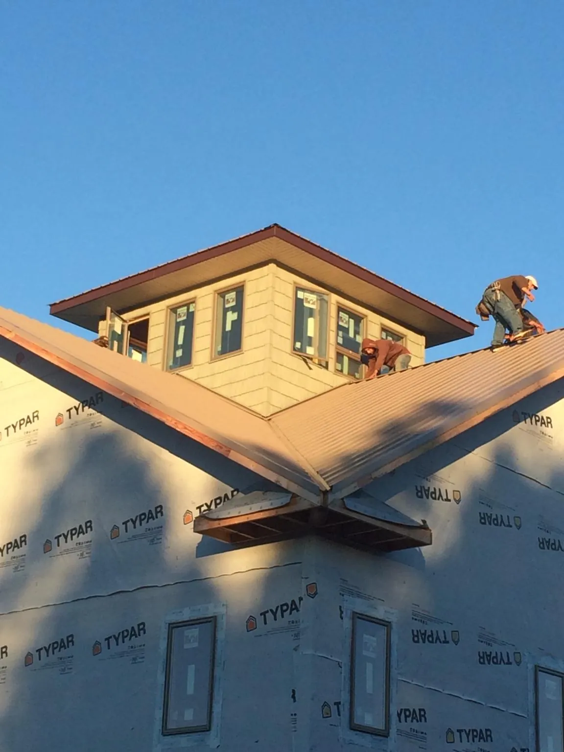 Roofers working around a rooftop cupola on a new metal roof at sunset — Roof Waterproofing in Zellwood by Roofing Brothers